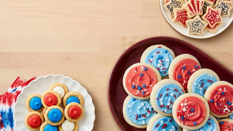Three plates with assorted red, white, and blue frosted cookies.