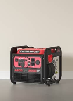 An image of a red and black power generator on a grey floor, against a beige wall.