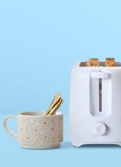 Coffee mug with spoon next to toaster.