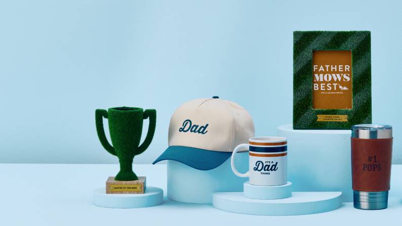 Green trophy, “Dad” hat, “It’s a Dad thing” mug, picture frame, insulated cup. Text reads: from nine dollars and ninety-seven cents.