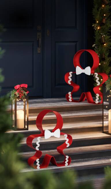 Standing gingerbread-man-shaped bow ornaments and candle lanterns shown on doorsteps.