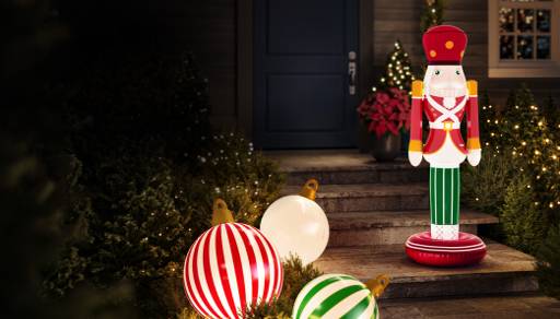 Large inflatable baubles and traditional toy soldier shown in a festive front yard setting with trees and lights.