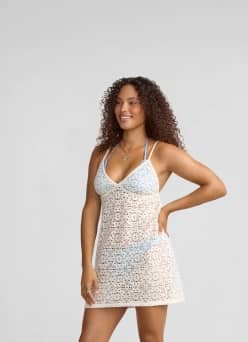 A woman is shown wearing a white lace spaghetti strap dress swim cover-up.