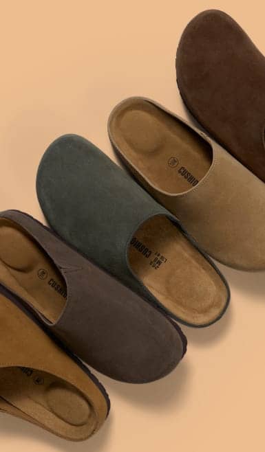 Five pairs of unbranded slip on suede clogs in assorted neutral colors arranged in a diagonal pattern.