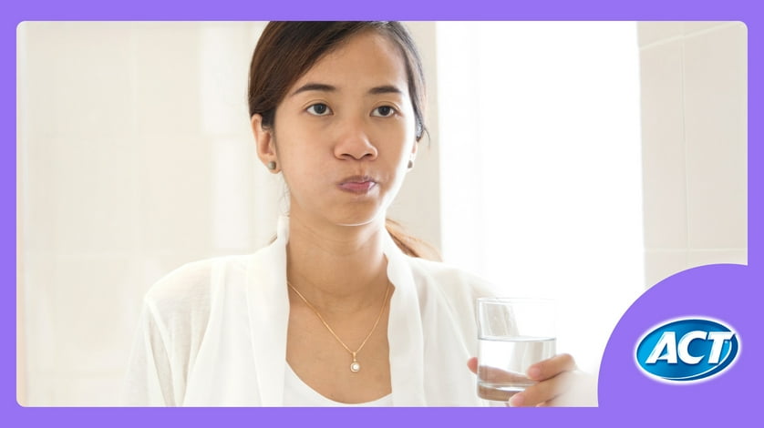 A person washes their mouth with mouthwash while holding a clear glass.