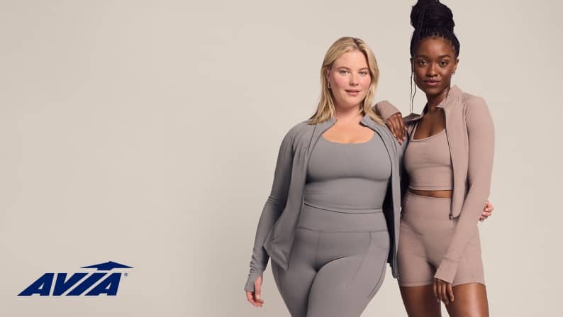 Two young adult women are shown, each wearing matching workout sets. Avia logo is seen.