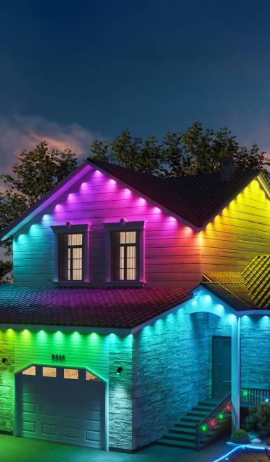 Rainbow-colored lights decorating the eaves of a house at night.