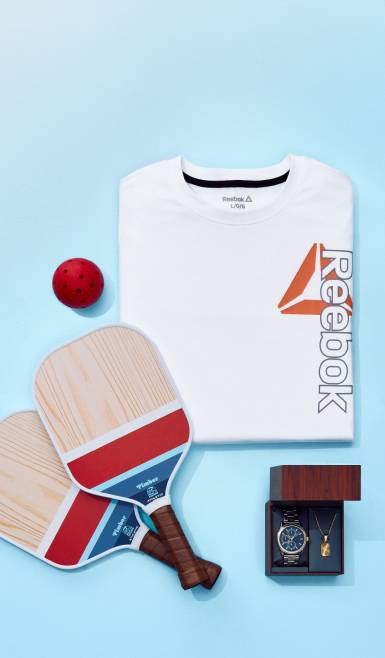 Reebok athletic shirt, pickleball paddle set, and open jewelry box containing a wristwatch and gold necklace.