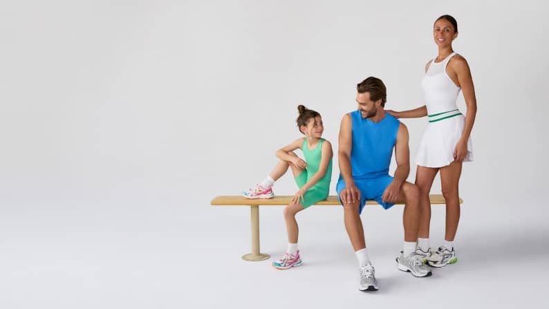 A family of three is posing together in colorful active sets.