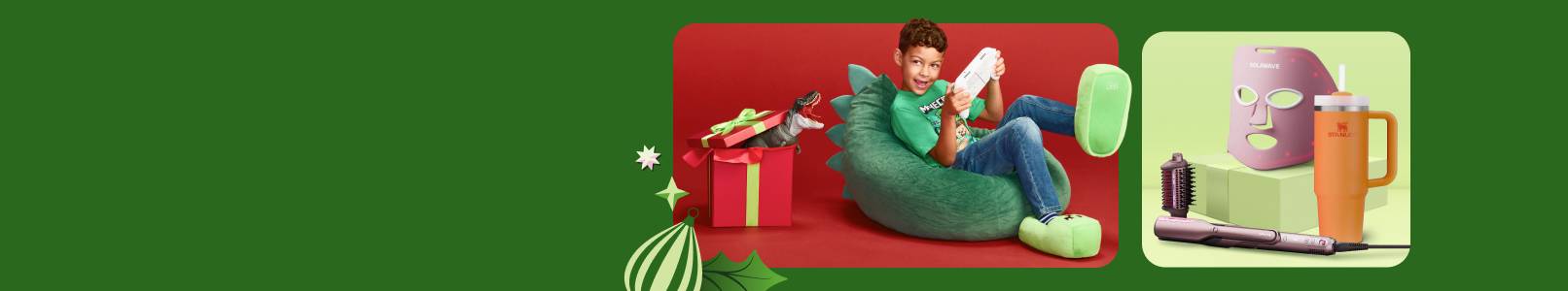 A boy is playing a video game on a beanbag chair. A dinosaur is coming out of a gift box. A Shark hair straightener, Solawave mask and a Stanley cup.