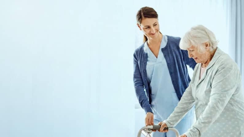 A health professional assisting an elderly woman.