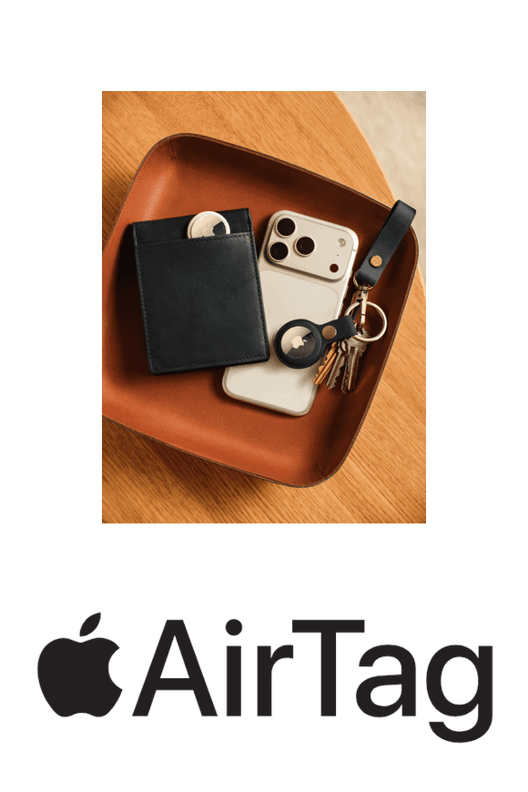 Image shows an Apple AirTag with a leather wallet, a smartphone and a keyring organizer in a leather tray on a table with a light wood background.