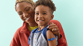 A child smiling with a bandage on their arm.