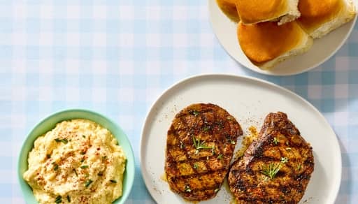A plate with meat, next to a bowl of potato salad and a stack of buns alongside an Express Delivery logo.