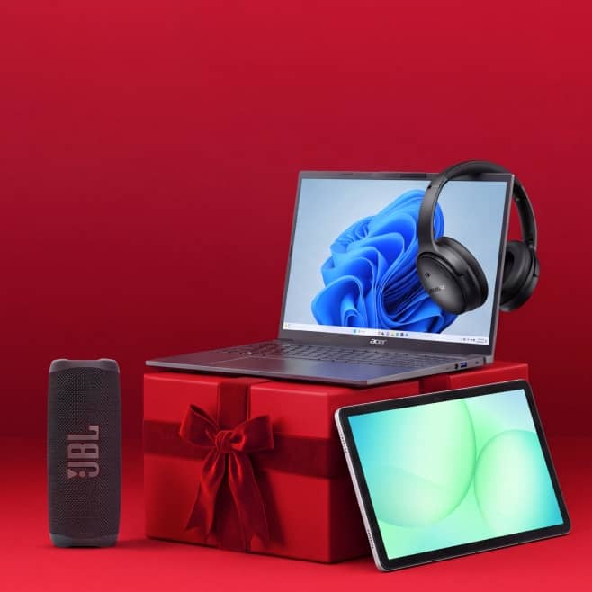 Acer laptop with blue abstract screen, black over ear headphones, JBL portable speaker and tablet arranged as holiday tech gifts.
