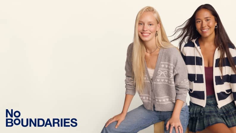 Two women in casual fits, one in jeans and a gray cardigan, the other in a striped hoodie with a plaid mini skirt.