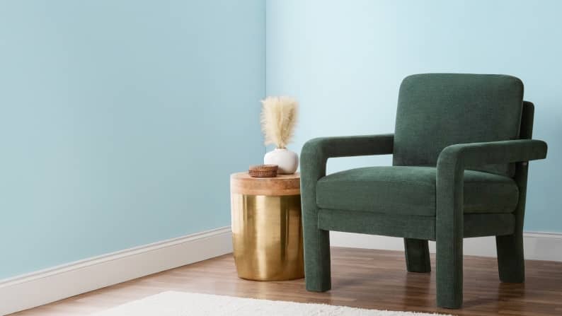Image of green accent chair & gold side table with decor.