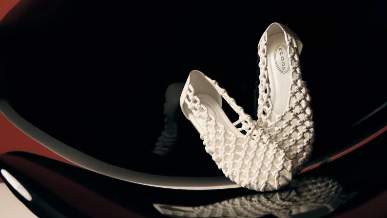 Pair of cream woven ballet flats with an open lattice design displayed against a black reflective background.