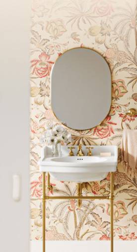 Floral peel-&-stick wallpaper behind a bathroom sink & mirror.