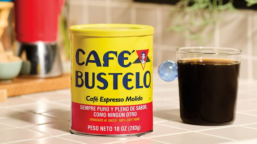 A can of Cafe Bustelo next to a big cup of the coffee beverage.