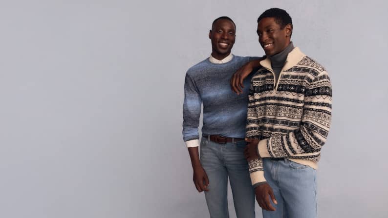 Two men are shown. One wears a Fair Isle quarter zip sweater over a gray turtleneck. Other wears a blue ombre crewneck sweater over a white shirt.