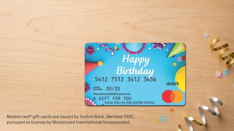 A Happy Birthday gift card on a wood table, surrounded by confetti.