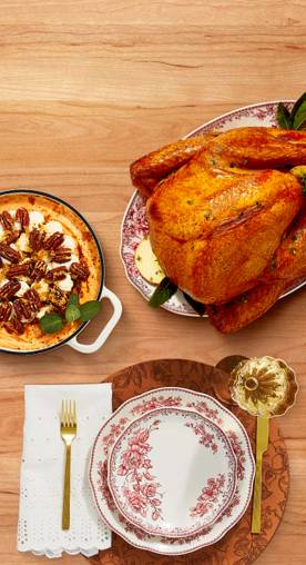 A fully cooked turkey, a pecan pie and a table setting is shown.