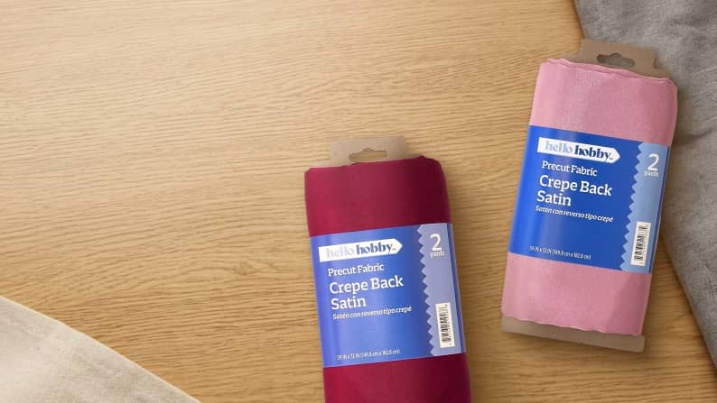 Banner taken overheard of crafting table, two fabric swatches, and text: Stitch it, style it, love it. New from Hello Hobby. Shop now.