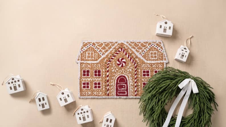 Gingerbread style house wall decor with small white house ornaments and a green wreath with white ribbon.