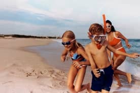 Shop now. A young boy, a young girl, and a woman with Speedo swimming accessories play in the ocean wearing Speedo swimsuits.