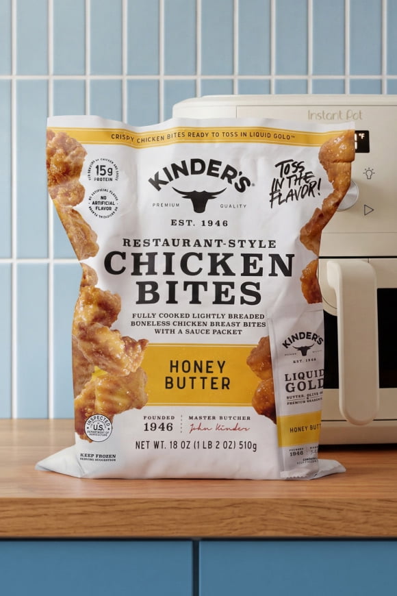 A bag of frozen chicken bites from Kinder’s next to an air fryer.