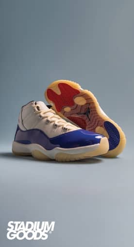 A pair of white and blue sneakers. One sneaker is flipped on its side, showing a red sole.