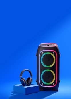 Party speaker with dual circular light rings and over ear headphones on a block.