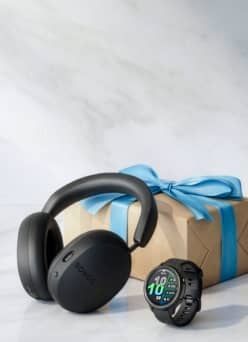 Sonos headphones and Garmin watch in front of wrapped gift box.