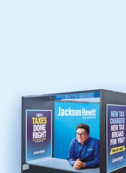 A man sitting in a Jackson Hewitt kiosk booth.
