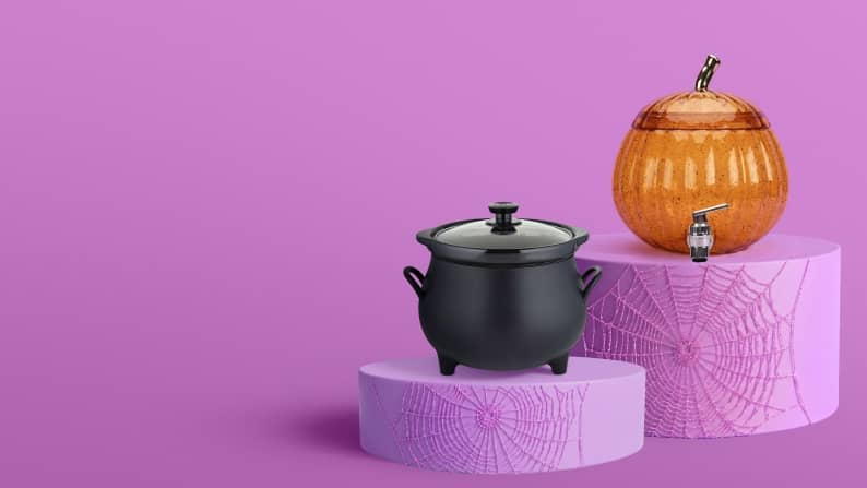 A black cauldron pot and an orange pumpkin-shaped drink dispenser sit on purple pedestals.