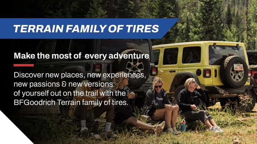 A group of people sit on the ground in a forest by a Jeep that is equipped with BF Goodrich Terrain tires.
