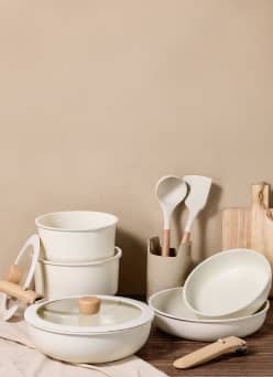 A stack of matching beige pots and dishes including a cutting board.