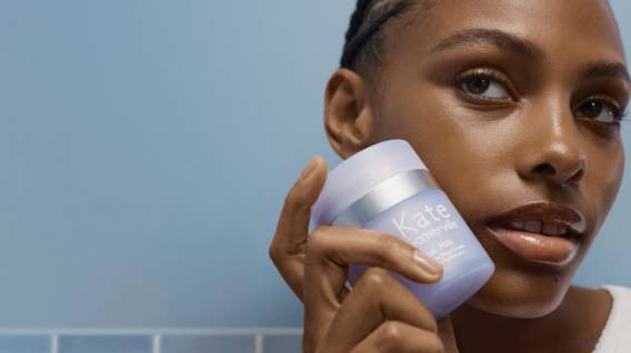 Image of a woman holding a skincare product near her face is shown.
