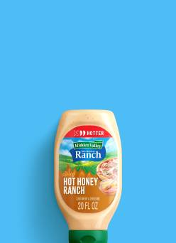 A bottle of Hidden Valley Hot Honey Ranch is shown next to a Smash Kitchen Hot Honey BBQ sauce bottle.