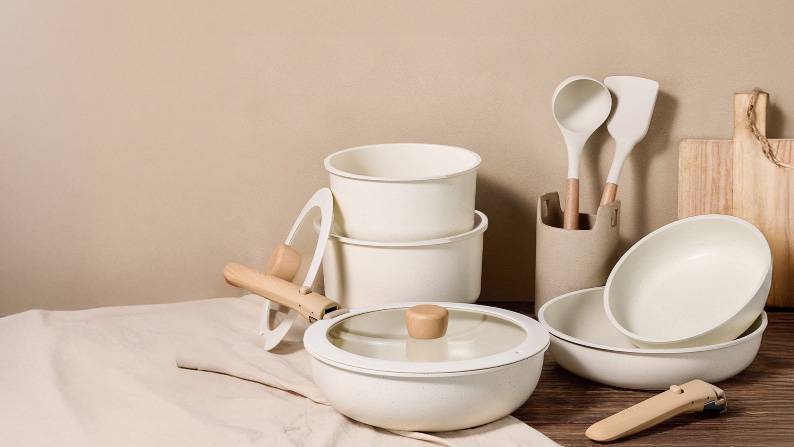 A stack of matching beige pots and dishes including a cutting board.