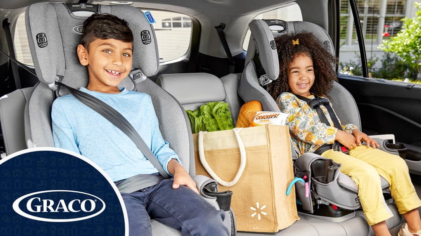Two children sit in Graco carseats inside a vehicle.