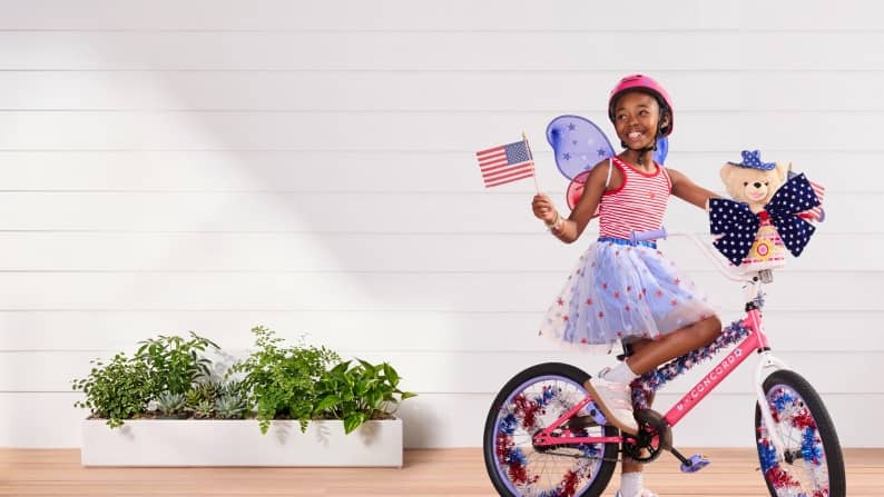 A girl rides a red, white and blue bike wearing a red, white, blue outfit.
