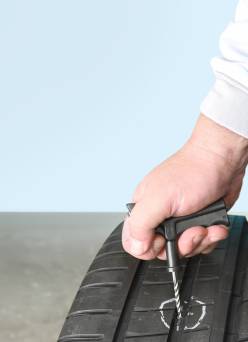 A person's hand repairing a tire.