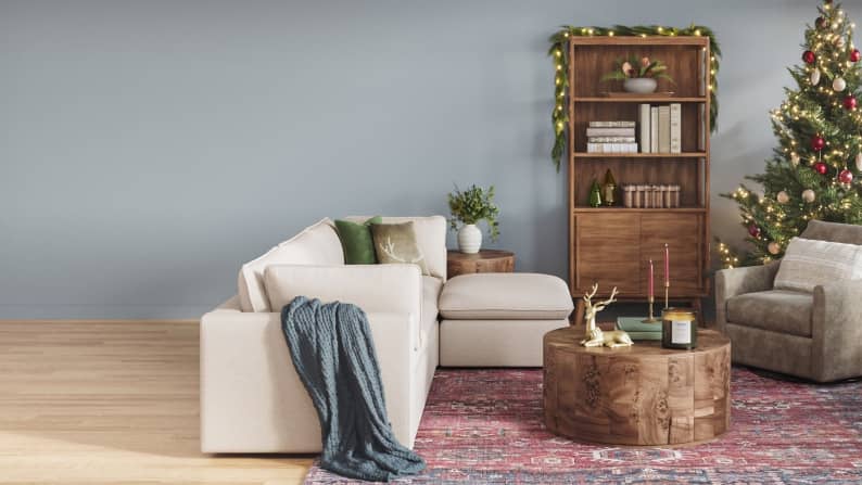 A dusty blue living room features an accent chair, coffee table, Christmas tree and festive decor.