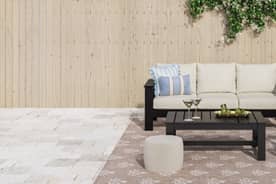 A dark brown metal rectangular patio table with a light blue umbrella. Chairs with white cushions and a blue-and-white striped accent pillow.