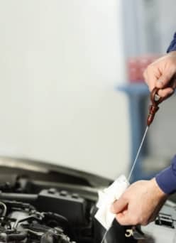 A hand working under the hood of a car.