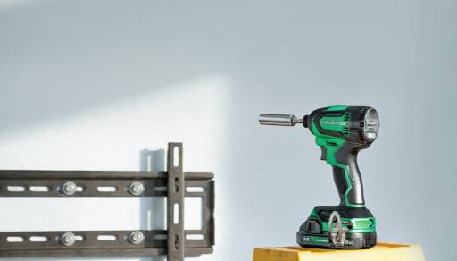 A green drill in front of a pale blue wall, next to a TV mount.