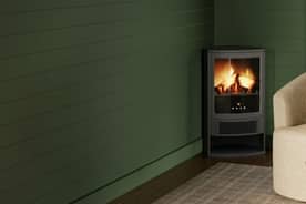 An image of a green fireplace against a green wall, next to an ivory chair.