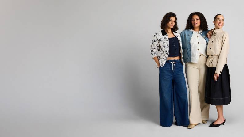 Three women pose wearing a mix of denim and canvas jeans, pants, and jackets featuring solid and floral prints.